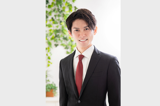 緑を背景に微笑む男性